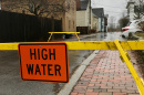 Flooded road blocked with yellow tape and "high water" sign