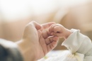 A photograph of an adult and baby holding hands