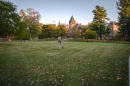 Student walking across lawn, T Hall in the background 