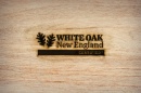 Logo with leaves and words "White Oak New England Certified" are branded on piece of wood