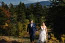 Married couple on wedding day walking in front of colorful trees and mountains