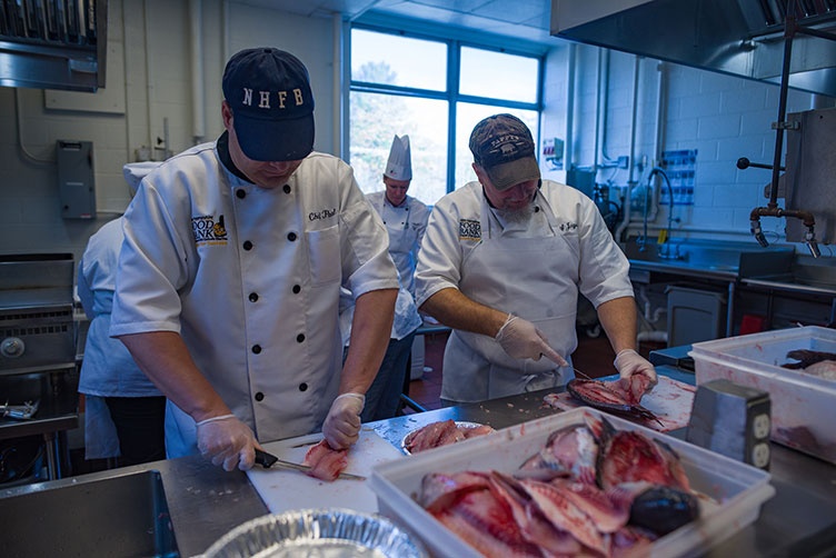 Chef Paul Morrison and Chef Jayson McCarter of the N.H. Food Bank’s Recipe for Success program help to filet the UNH donated tilapia