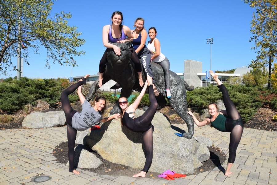 The UNH aerial squad poses in front of the wildcat statue.