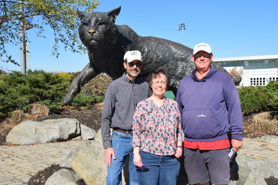 Three UNH alumni pose in front of the wildcat