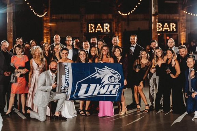 Large group of UNH alums pose with bride and groom at wedding