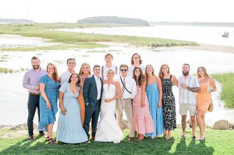 Large group of family and friends pose with bride and groom at wedding