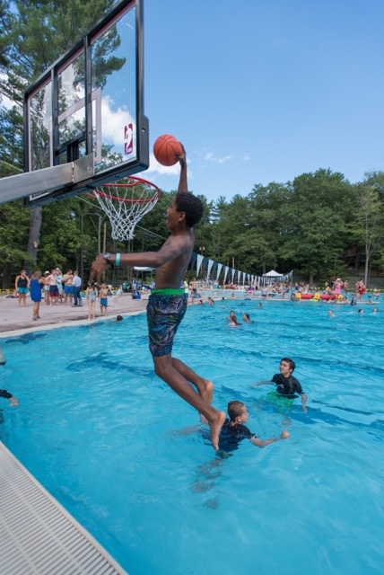kid playing water basketball at the opening of UNH's new outdoor pool