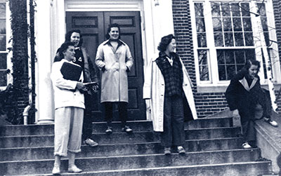 Female students outside academic building in blue jeans (dungarees)